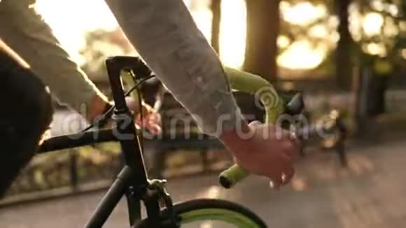 在晨间公园或林荫大道上拍摄舵手骑自行车的镜头一个年轻人骑着一辆视频的预览图