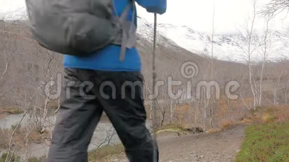 一个带着背包沿着山路行走的中年男子他旅行并过着健康的生活方式视频的预览图