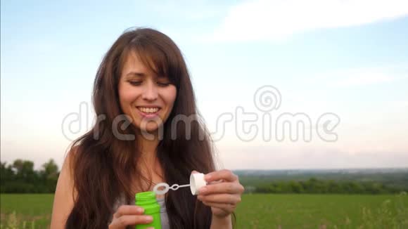 女人在蓝天上吹着透明的肥皂泡然后慢动作视频的预览图