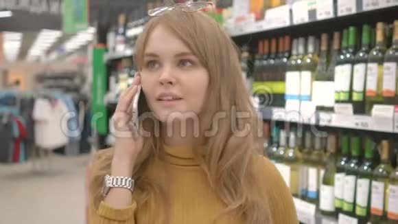 有手机的女人说话决定在超市买什么酒视频的预览图
