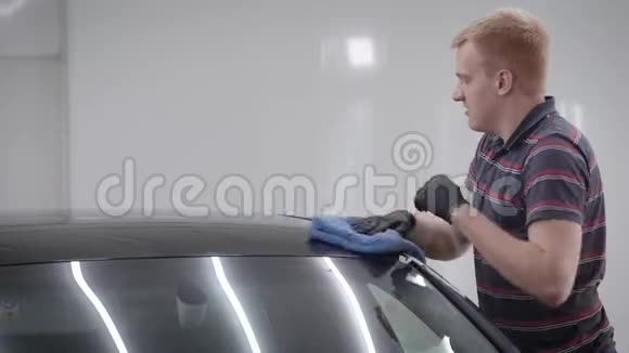 车库用蓝色毛巾擦拭车顶的人侧视图视频的预览图