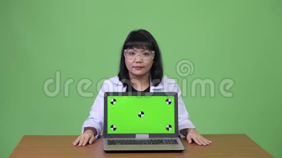 美丽的亚洲女医生戴着防护眼镜手提电脑视频的预览图