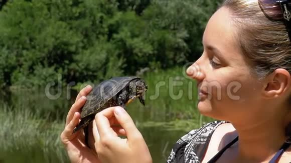 女人手里拿着一只小河龟靠近大自然的脸慢动作视频的预览图