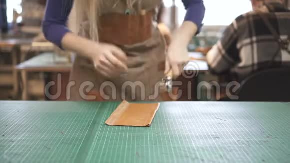 女鞋匠手按在人造皮革细节与滚动工具在工作室视频的预览图