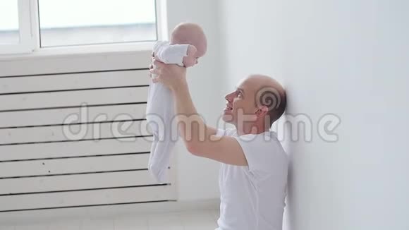 年轻快乐的父亲和他的孩子在白色的室内度过时光视频的预览图