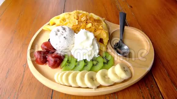 甜水倒在华夫饼上冰淇淋和水果包括香蕉猕猴桃和草莓放在木盘上视频的预览图