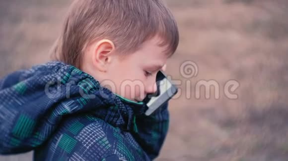 男孩在公园里用手机说话特写面部侧视视频的预览图