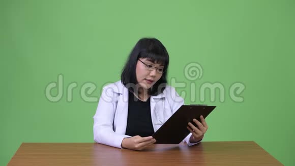 美丽的亚洲女医生拿着夹子说话视频的预览图