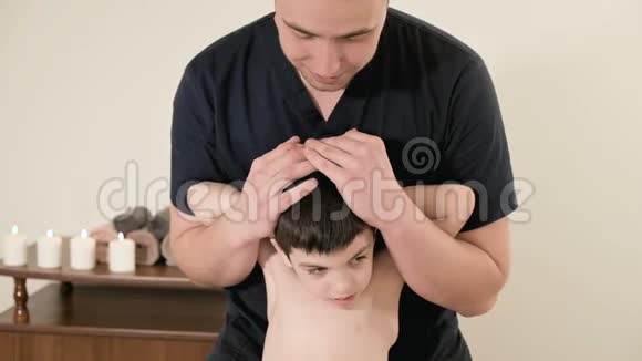 年轻男性理疗师按摩师在按摩室为一个小孩做背部和脊柱的伸展治疗视频的预览图
