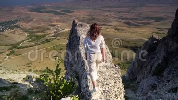 女人走在岩石的年代面对美丽的风景视频的预览图