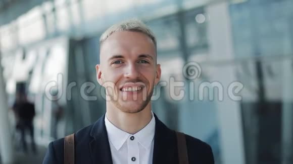 微笑的年轻商人的肖像背包站在机场外看着镜头视频的预览图
