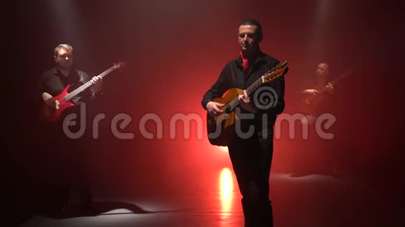 舞者用双手演奏吉他上的音乐从后面的光吸烟背景视频的预览图