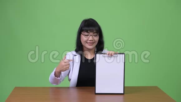 美丽的亚洲女医生展示剪贴板竖起大拇指视频的预览图
