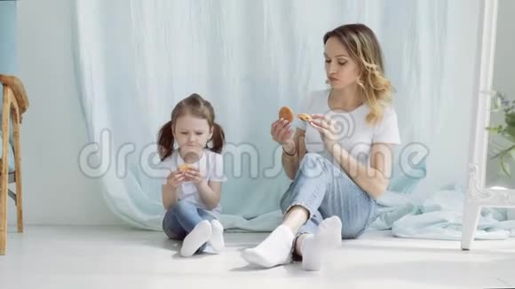 一个漂亮的女人手里拿着饼干的小女孩坐在地板上说话视频的预览图