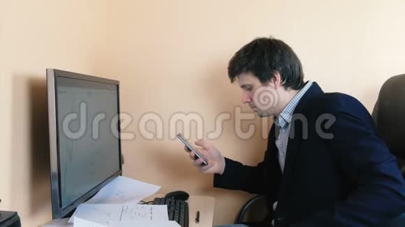 人类正在浏览他在电脑上工作的手机视频的预览图