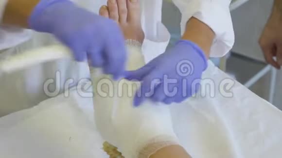医生他的手是特写的这使一个生病的女人的脚上有绷带视频的预览图