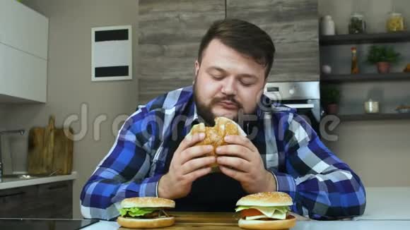 厚个子吃东西喜欢他的汉堡包有胡子的人吃他做的食物不健康的生活方式油炸和高视频的预览图