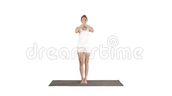 漂亮的女孩站在平衡瑜伽姿势Garudasana年轻女子在鹰瑜伽姿势的白色背景视频的预览图