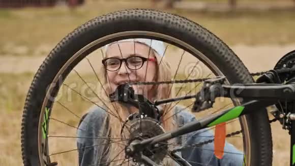 一个11岁的女孩扭扭捏捏地看着她自行车的车轮视频的预览图