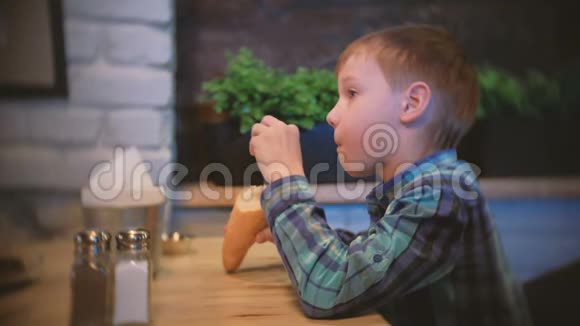 男孩在咖啡馆里吃面包和看电视侧视视频的预览图