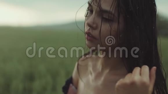 近距离观看一位美丽的年轻女子裸露的肩膀被雨水浸透雨滴落在美丽的女人脸上视频的预览图