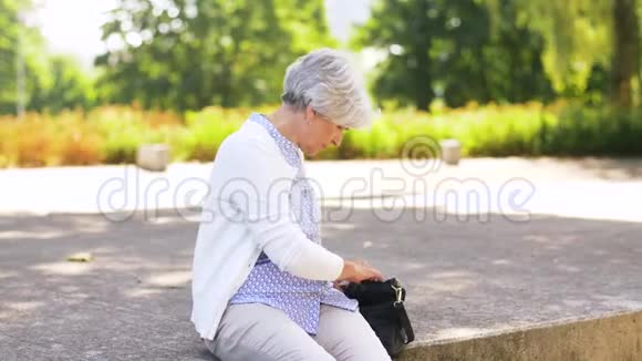 在公园里拿智能手机的老太太视频的预览图