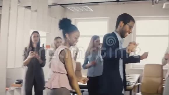 两个非裔美国朋友在办公室聚会上一起跳舞多民族商务人士工作乐趣4K视频的预览图