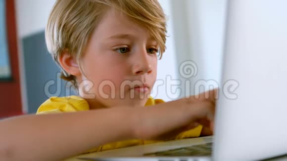 可爱的白人学生坐在桌子上在教室里使用笔记本电脑视频的预览图