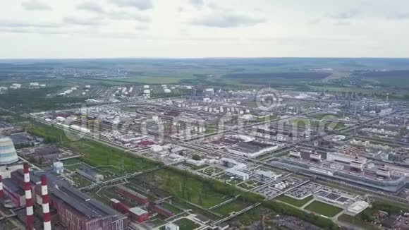 油气化工厂背景上有绿色的田野和多云的天空剪辑在工厂里抽烟的烟囱视频的预览图