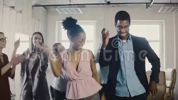 美国黑人男女雇员在办公室聚会上与多民族同事跳滑稽的民族舞蹈视频的预览图