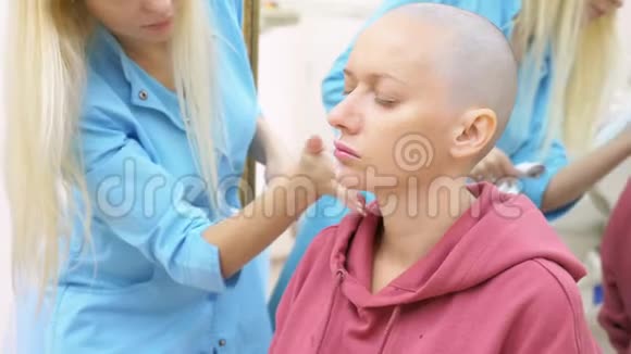 在美容师的约会中时髦的秃头女人在脸上涂上麻醉霜视频的预览图