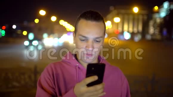 迷人的西班牙裔男人用手机带着美丽的微笑帅哥在拥挤的人群中使用智能手机视频的预览图