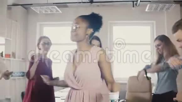 快乐的非裔美国女人在办公室聚会上跳舞多种族的同事跳舞分享有趣的粘合时间在一起4K视频的预览图
