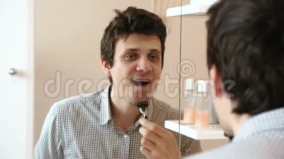 人在照镜子时刮胡子穿着格子浅色衬衫的布鲁内特视频的预览图