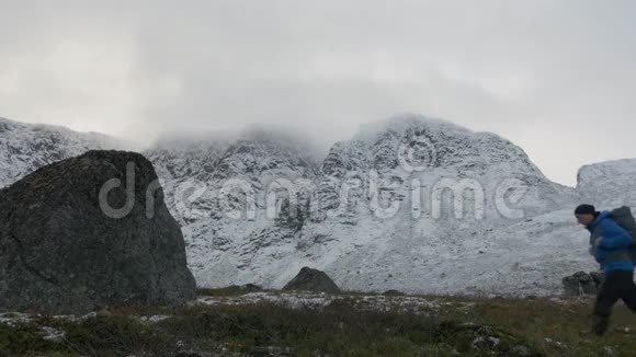 一个背着背包的人独自一人在山里旅行它沿着高高的雪峰视频的预览图