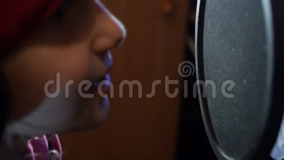 戴着耳机的小女孩在录音室对着麦克风唱歌视频的预览图