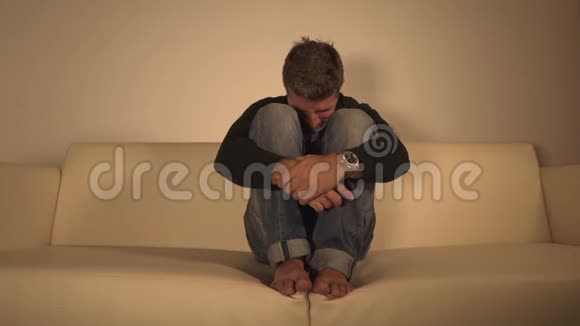 年轻迷人的沮丧和悲伤的阴暗男人在家里的沙发上哭泣在痛苦和绝望中迷失焦虑危机和抑郁视频的预览图