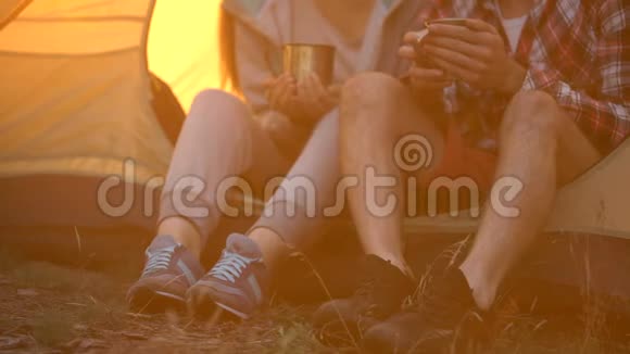 朋友们穿着舒适的鞋子坐在帐篷里喝茶在森林里徒步旅行视频的预览图