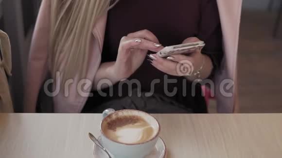 在城市咖啡馆里美丽的女孩在休息时发短信喝咖啡视频的预览图