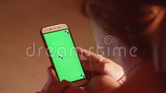 带绿色屏幕和跟踪点的女孩手持手机的背面视图视频的预览图