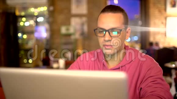 在城市咖啡馆里用笔记本电脑工作的年轻人一个年轻迷人的时髦女郎在咖啡馆里有一个现代的内部他在工作视频的预览图