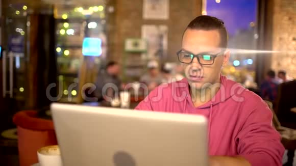 年轻英俊的商人学生在桌子上用笔记本电脑工作戴着眼镜微笑概念新视频的预览图