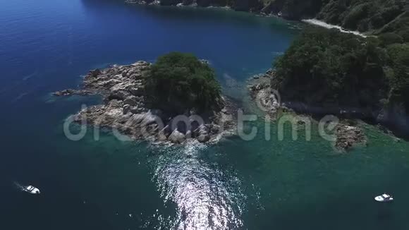 热带雨林覆盖的小岛上的空中森林周围的石岸带漂亮的水晶海水视频的预览图