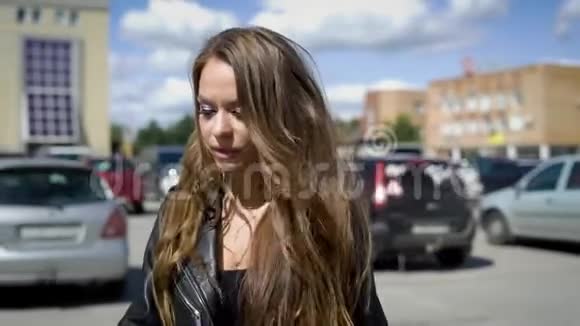 一个年轻漂亮的女人走在街上在汽车和现代城市设施中一位女士看起来很高兴视频的预览图