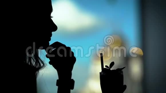 一个女人用吸管喝鸡尾酒的轮廓这位女士在一家餐馆里喜欢喝酒视频的预览图