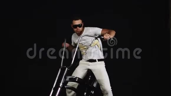 戴太阳镜的白衣男子坐在自行车上按下刹车转动车把视频的预览图