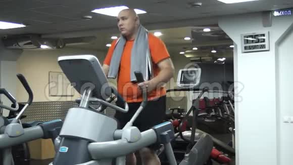有趣的胖子在健身房用汉堡做椭球运动视频的预览图