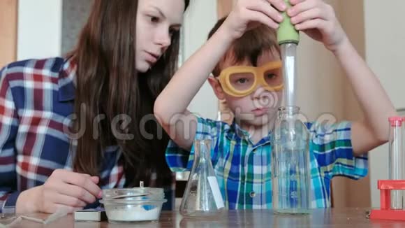 在家做化学实验男孩用一个大吸管把瓶子里的水倒进瓶子里视频的预览图