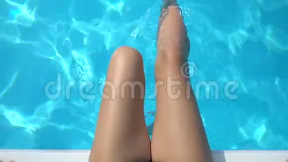 在游泳池里用纯蓝色的水把女人的双腿和水玩起来视频的预览图