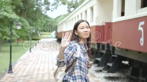 4K亚洲女游客在火车站的列车上挥手告别再见视频的预览图